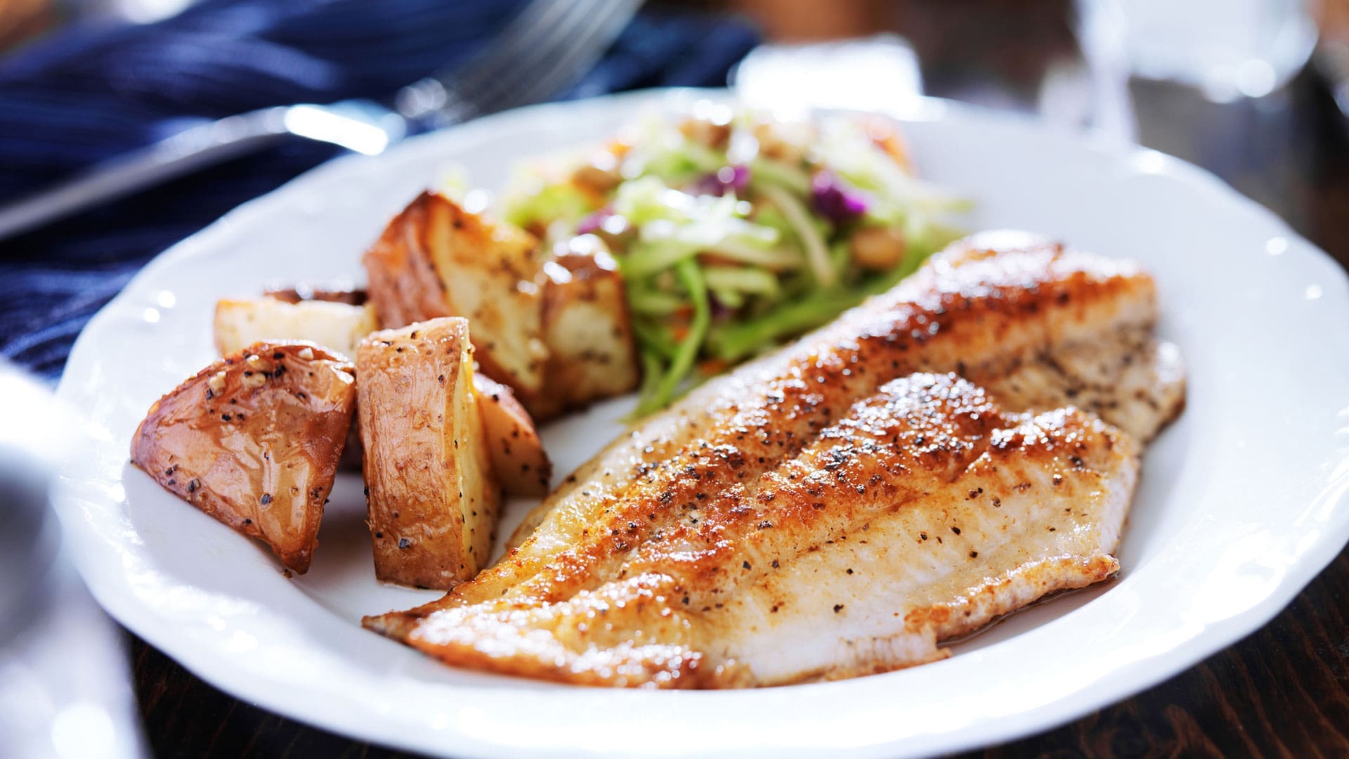 Plate of seared fish with roasted potatoes and slaw