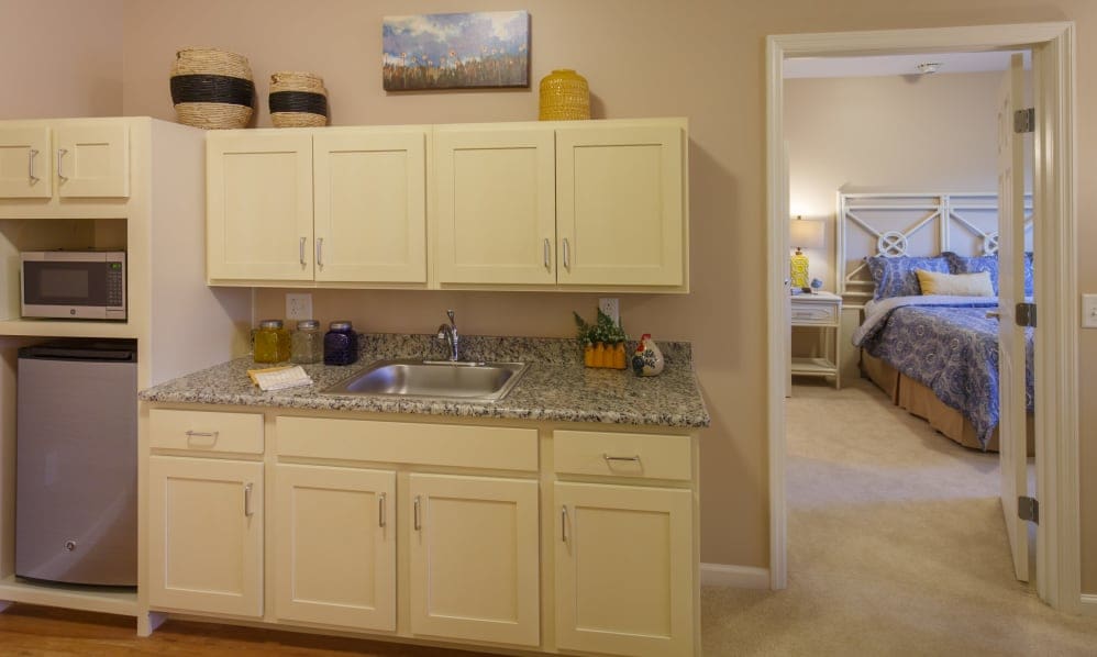 Apartment kitchenette with microwave and mini fridge, next to the bedroom